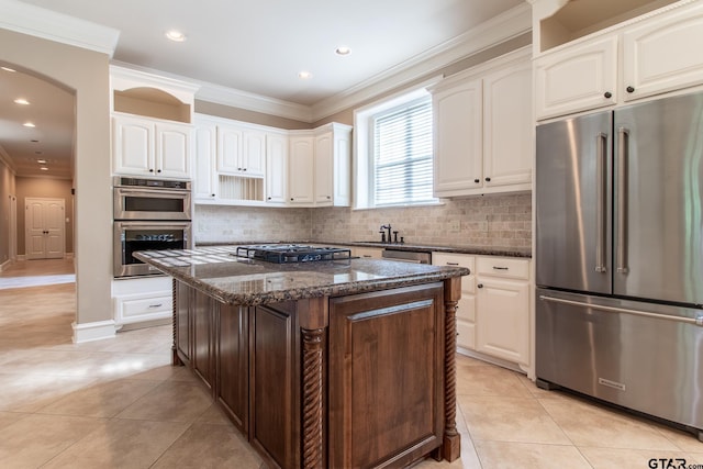 kitchen with light tile patterned flooring, stainless steel appliances, a center island, and dark stone counters