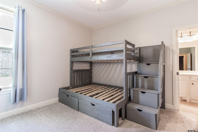 carpeted bedroom featuring ensuite bath, ornamental molding, and ceiling fan