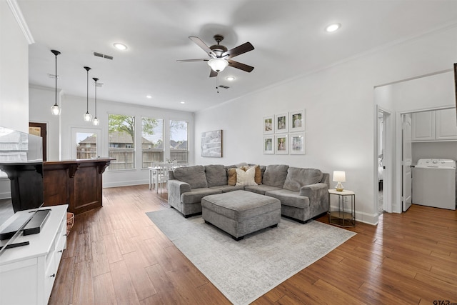 living room featuring washer / dryer, crown molding, a ceiling fan, and visible vents