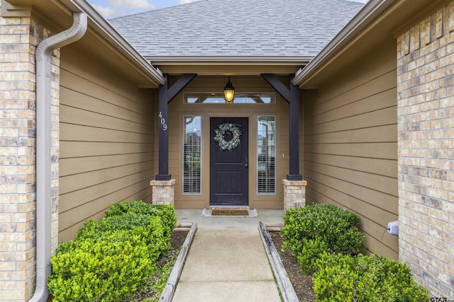 entrance to property featuring a shingled roof