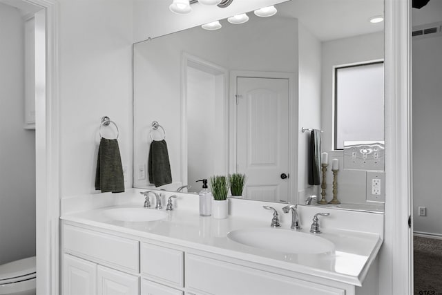 full bathroom with double vanity, toilet, and a sink