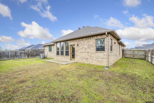 back of house featuring cooling unit, a patio, a fenced backyard, brick siding, and a yard