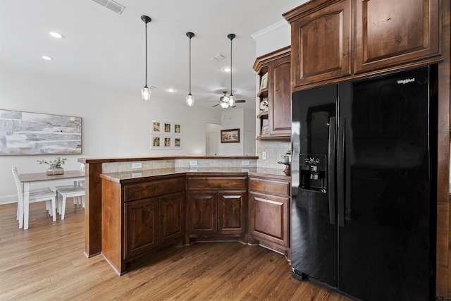 kitchen with black fridge with ice dispenser, decorative backsplash, a peninsula, ceiling fan, and light wood-style flooring