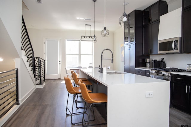 kitchen with an island with sink, dark hardwood / wood-style floors, a kitchen breakfast bar, and appliances with stainless steel finishes