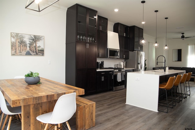 kitchen with stainless steel appliances, sink, a kitchen island with sink, dark hardwood / wood-style floors, and decorative light fixtures