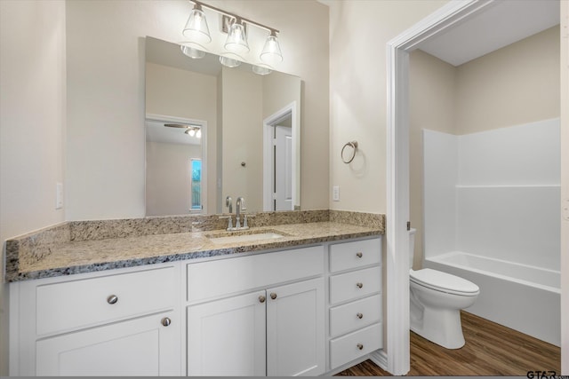 full bathroom with hardwood / wood-style floors, vanity, toilet, and tub / shower combination