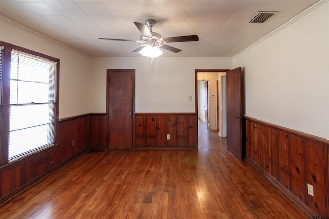 spare room with a wealth of natural light, wainscoting, and visible vents