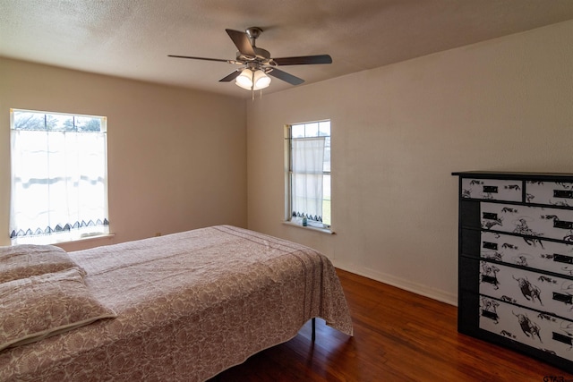 bedroom featuring a ceiling fan, a textured ceiling, baseboards, and wood finished floors