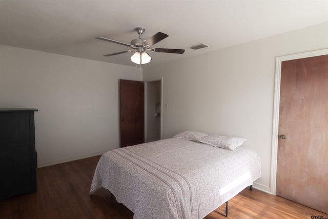 bedroom with a ceiling fan, visible vents, baseboards, and wood finished floors