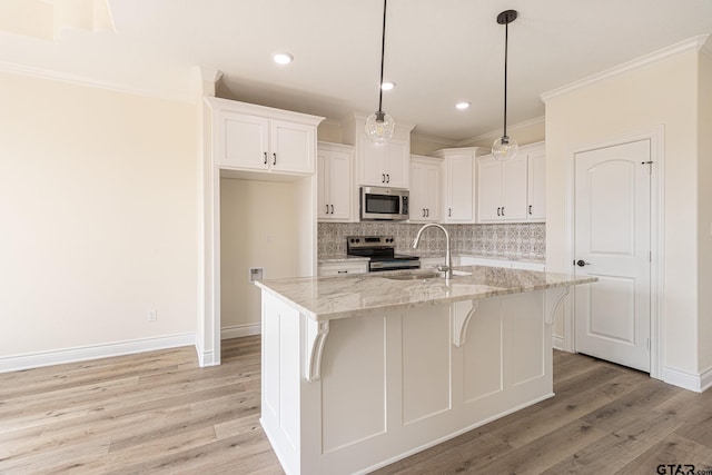 kitchen featuring white cabinets, light stone countertops, appliances with stainless steel finishes, and a kitchen island with sink