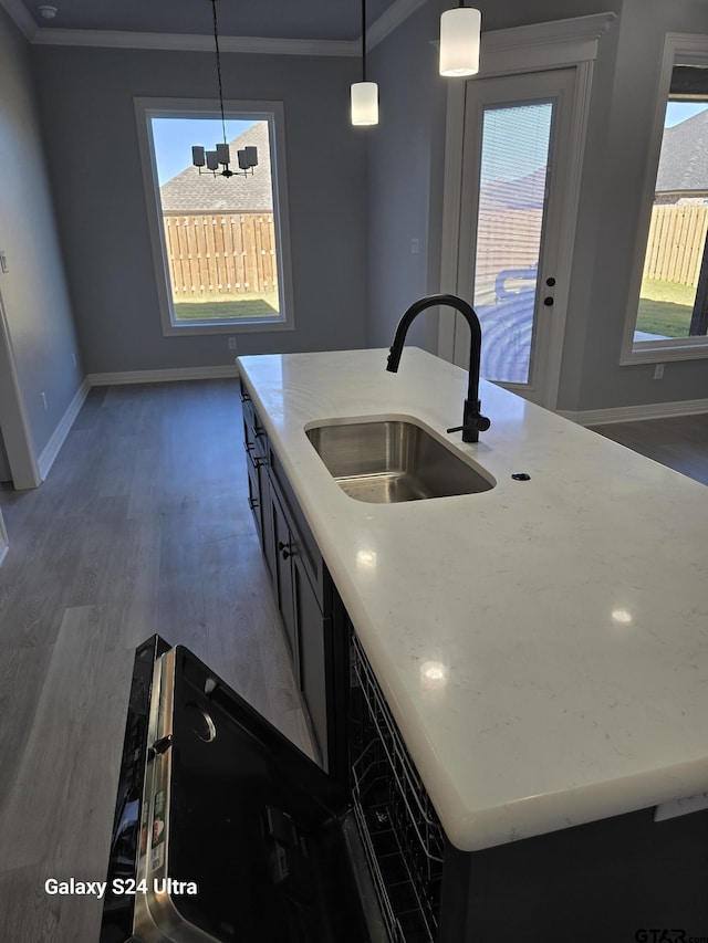 kitchen featuring dark wood-type flooring, decorative light fixtures, sink, and a center island with sink