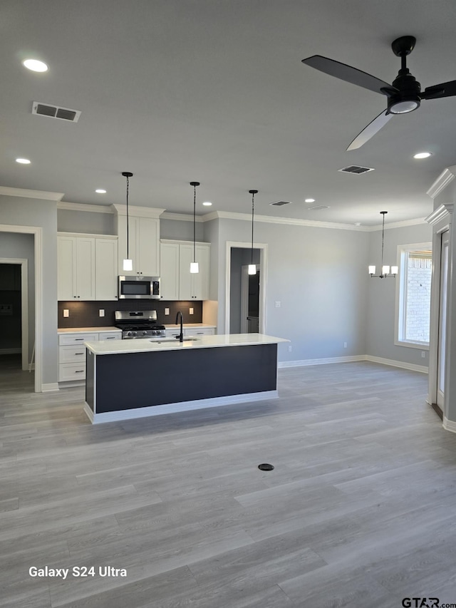 kitchen featuring stainless steel appliances, white cabinetry, a kitchen island with sink, and sink