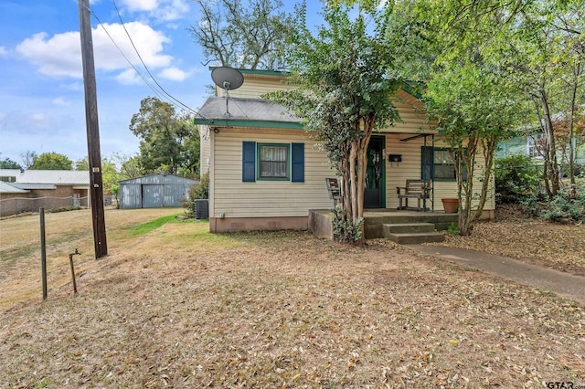 bungalow-style house with a storage shed, cooling unit, and covered porch