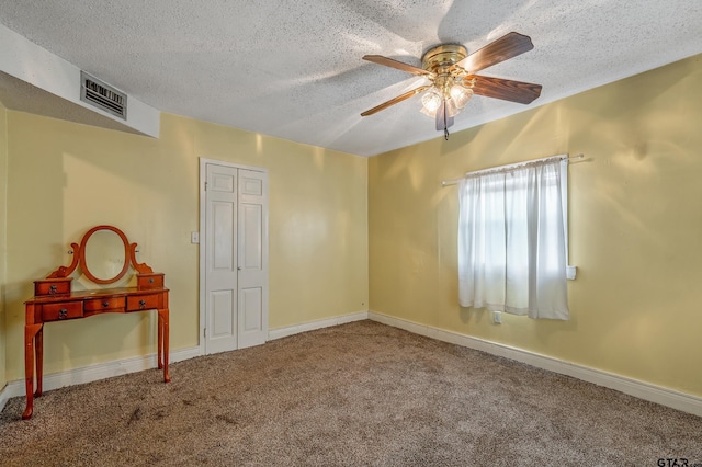 carpeted empty room with ceiling fan and a textured ceiling