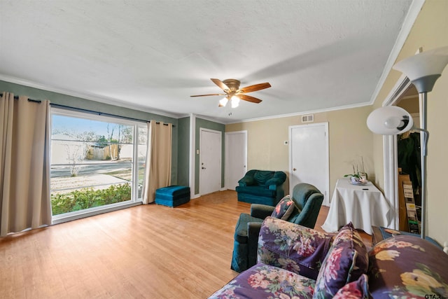 living room with a textured ceiling, light wood-type flooring, ceiling fan, and ornamental molding