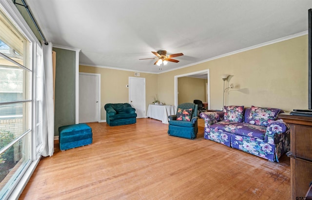 living room with ceiling fan, crown molding, and light hardwood / wood-style flooring