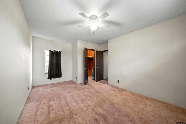 unfurnished bedroom with ceiling fan, a spacious closet, light carpet, and a closet