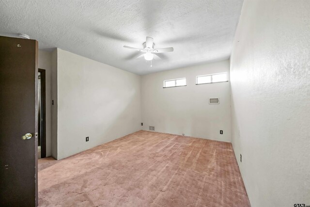 spare room with a textured ceiling, light colored carpet, and ceiling fan