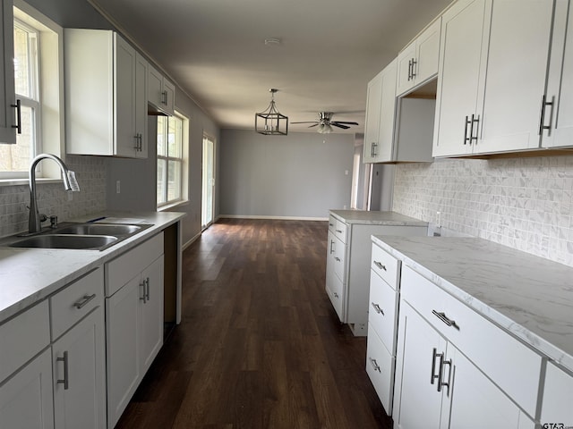 kitchen featuring dark wood-style floors, decorative backsplash, a sink, ceiling fan, and baseboards