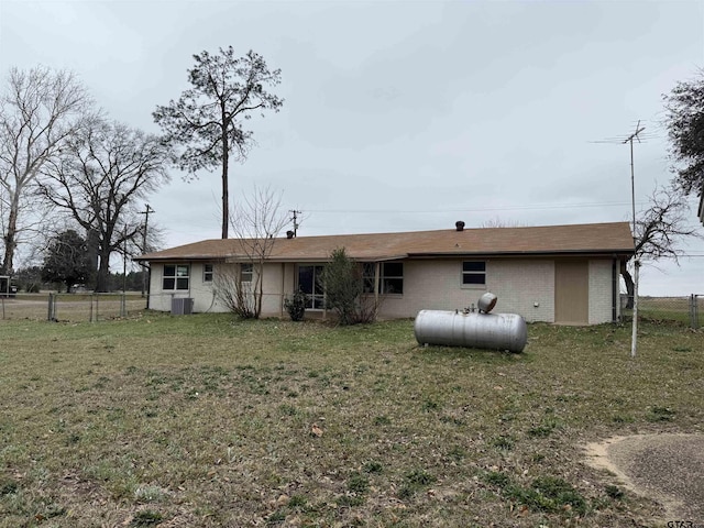 rear view of house featuring brick siding, a lawn, a gate, central AC, and fence