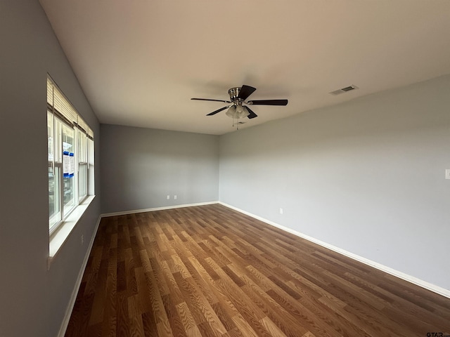 unfurnished room featuring dark wood finished floors, visible vents, and baseboards