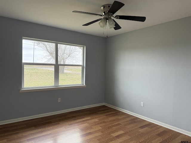 empty room with ceiling fan, baseboards, and dark wood-type flooring