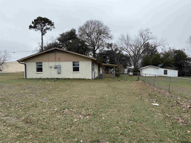 view of home's exterior featuring a detached garage, fence, a lawn, and brick siding