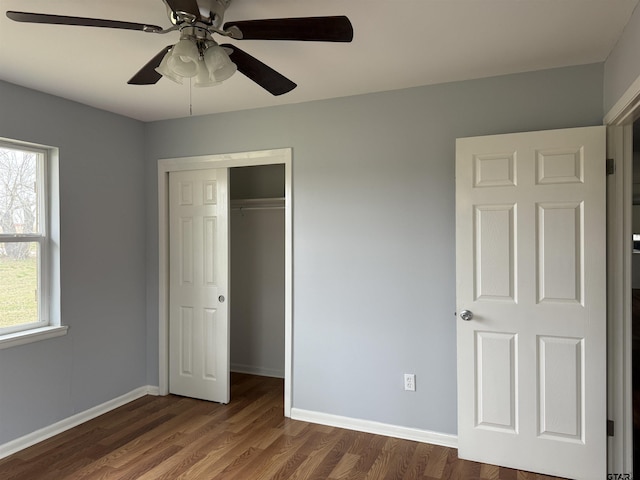 unfurnished bedroom featuring ceiling fan, dark wood-type flooring, a closet, and baseboards