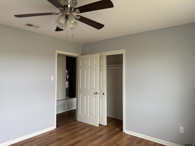 unfurnished bedroom with a closet, visible vents, dark wood finished floors, and baseboards