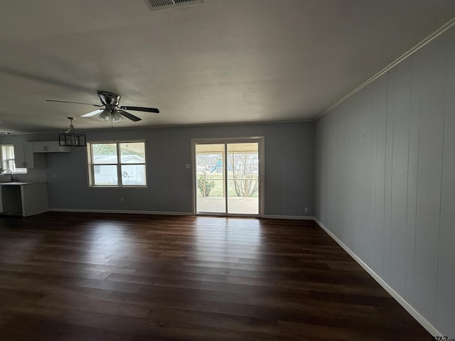 unfurnished living room with a ceiling fan, dark wood-style flooring, crown molding, and baseboards