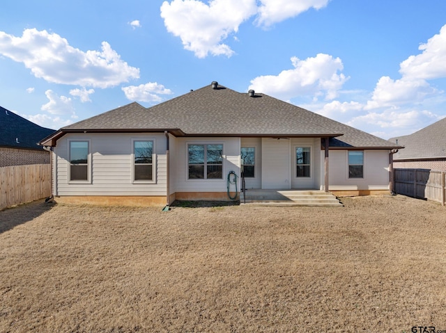 back of property with roof with shingles, a patio, and a fenced backyard