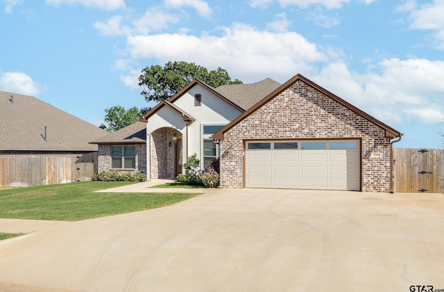 view of front facade featuring concrete driveway, a front lawn, brick siding, and fence