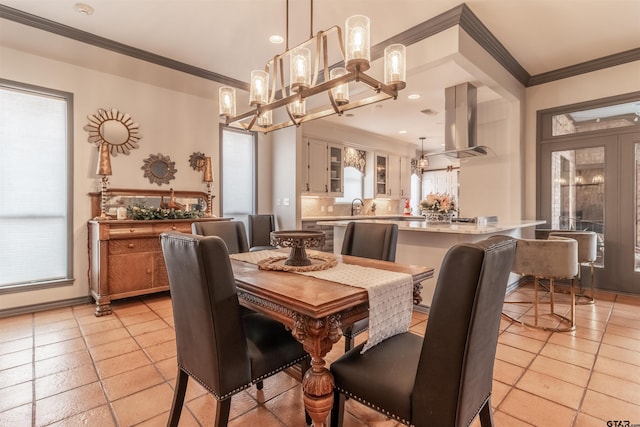 tiled dining room featuring crown molding, plenty of natural light, sink, and a chandelier