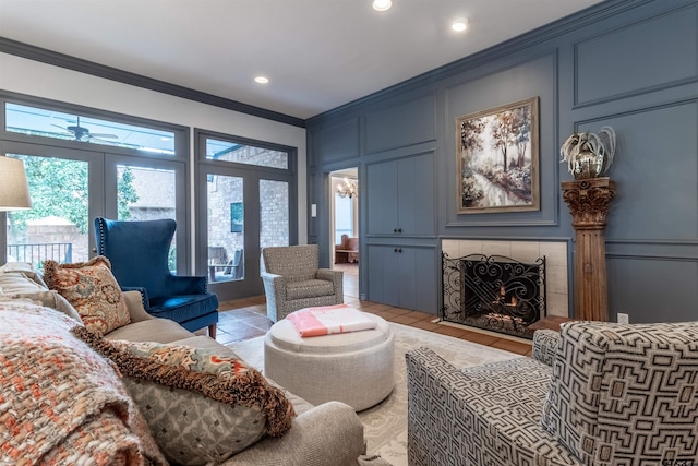 living room featuring ceiling fan, ornamental molding, a tile fireplace, and light tile patterned floors