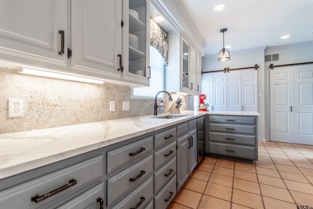 kitchen with sink, light stone counters, decorative backsplash, light tile patterned flooring, and decorative light fixtures