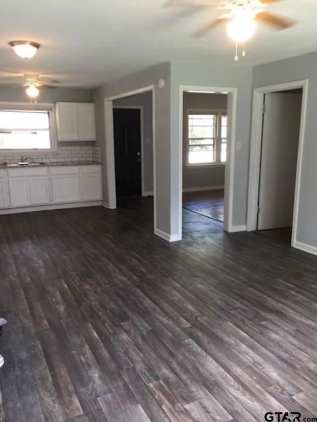 1108 Raney Dr, Longview, TX 75602 - unfurnished living room with ceiling fan, baseboards, dark wood-type flooring, and a sink
