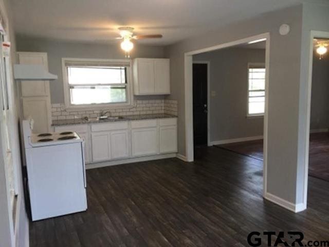 1108 Raney Dr, Longview, TX 75602 - kitchen with white range with electric stovetop, a ceiling fan, decorative backsplash, dark wood finished floors, and white cabinetry