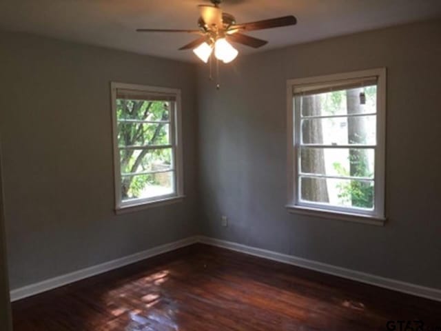 1108 Raney Dr, Longview, TX 75602 - unfurnished room with dark wood-style floors, ceiling fan, and baseboards