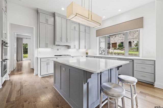 4645 Cascades Blvd, Tyler, TX 75709 - kitchen featuring appliances with stainless steel finishes, a kitchen breakfast bar, backsplash, light wood-type flooring, and recessed lighting