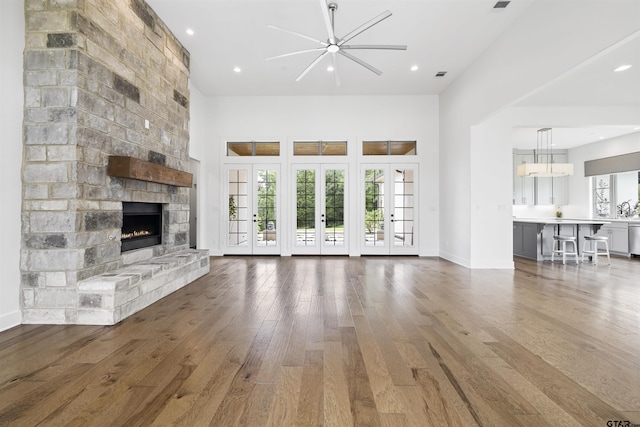 4645 Cascades Blvd, Tyler, TX 75709 - unfurnished living room featuring a fireplace, wood-type flooring, ceiling fan, a high ceiling, and french doors