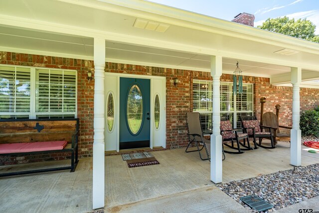 13094 Fm 2010, Chandler, TX 75758 - property entrance with covered porch, brick siding, and a chimney