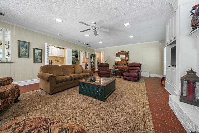 living room featuring ceiling fan, crown molding, and a textured ceiling