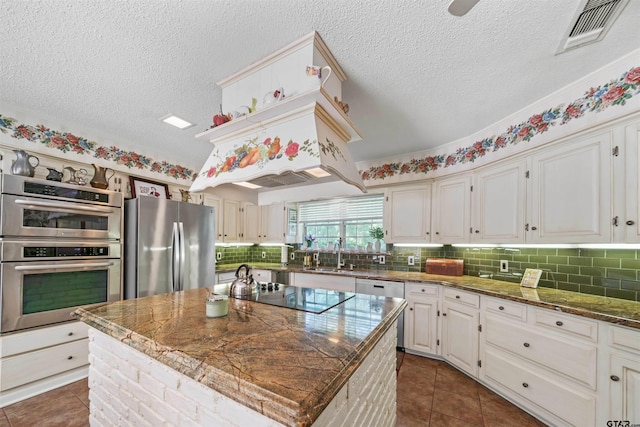 kitchen featuring a kitchen island, sink, stainless steel appliances, and dark stone counters