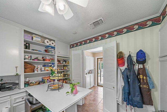 home office featuring ceiling fan, light tile patterned floors, and a textured ceiling