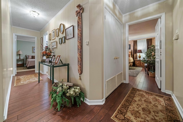 hall featuring crown molding, dark wood-type flooring, and a textured ceiling