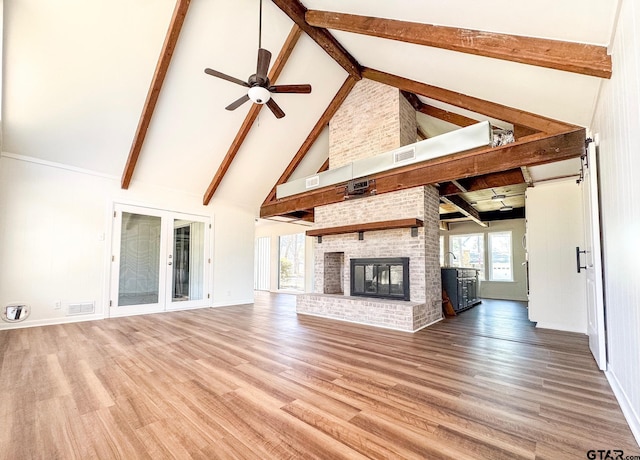 unfurnished living room featuring a fireplace, wood finished floors, visible vents, and a ceiling fan