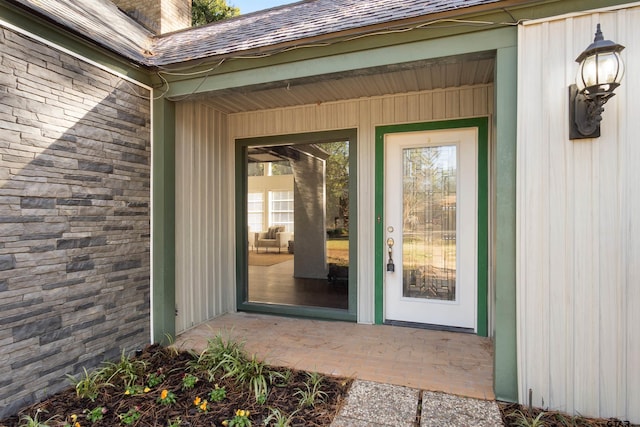 property entrance with stone siding and a shingled roof