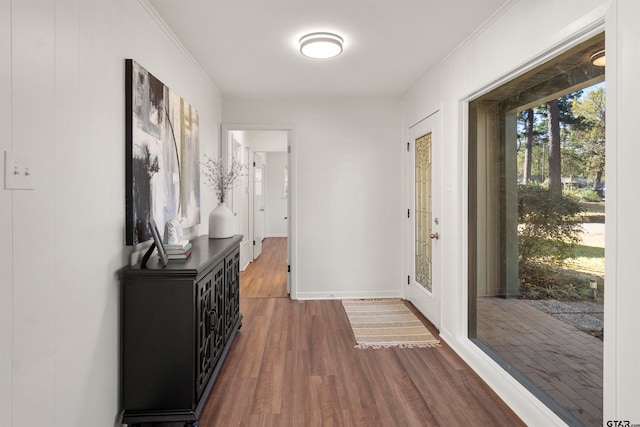 doorway featuring ornamental molding, dark wood-type flooring, and baseboards