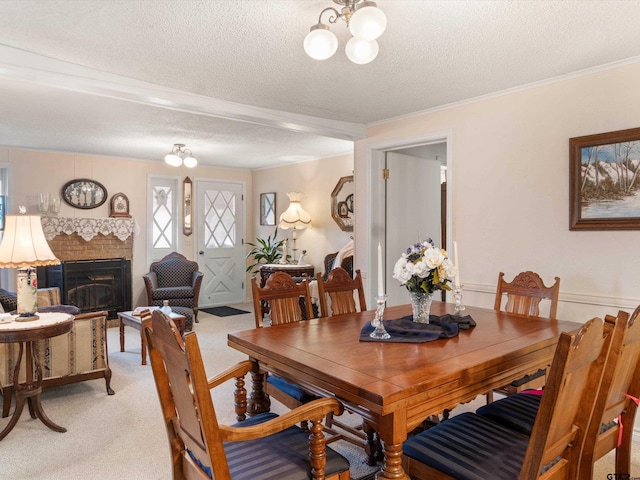 dining area featuring a textured ceiling, crown molding, light carpet, a fireplace, and an inviting chandelier