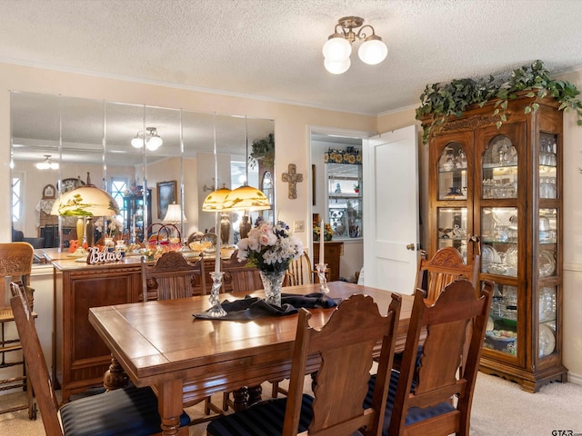 dining space with a textured ceiling, light carpet, ornamental molding, and a chandelier